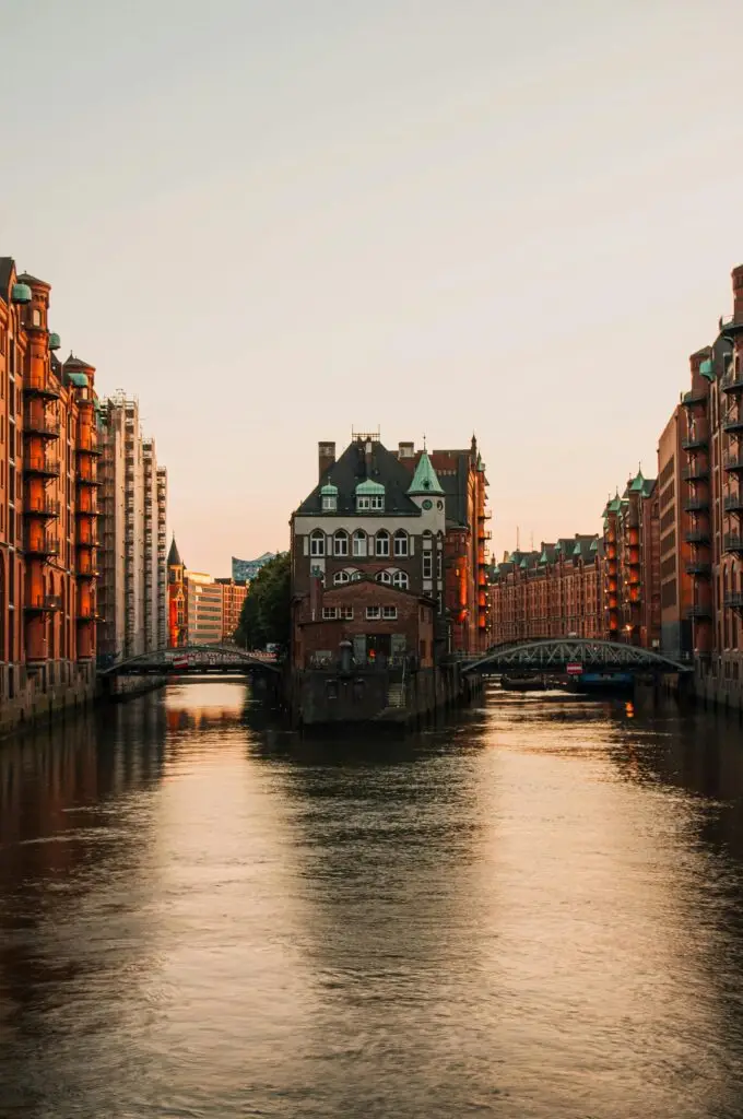 Scenic view of Speicherstadt district in Hamburg with historic architecture and calm water at sunset.